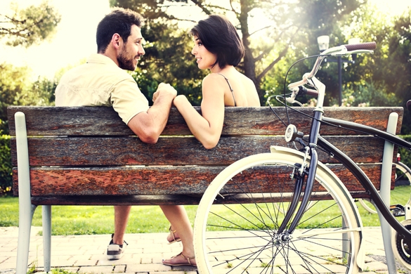 Couple in love sitted togheter on a bench with bikes
