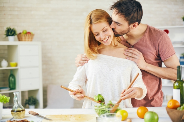 Affectionate young man kissing his wife while she cooking salad - How To Help A Taurus Man That Is Depressed