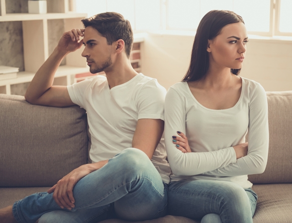 Beautiful young couple is having a quarrel while sitting on sofa at home - How To Get A Taurus Man To Stop Ignoring You