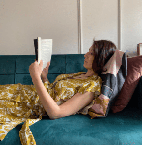 Anna Kovach astrologer book secrets Anna Kovach astrologer laying in her living room and reading book